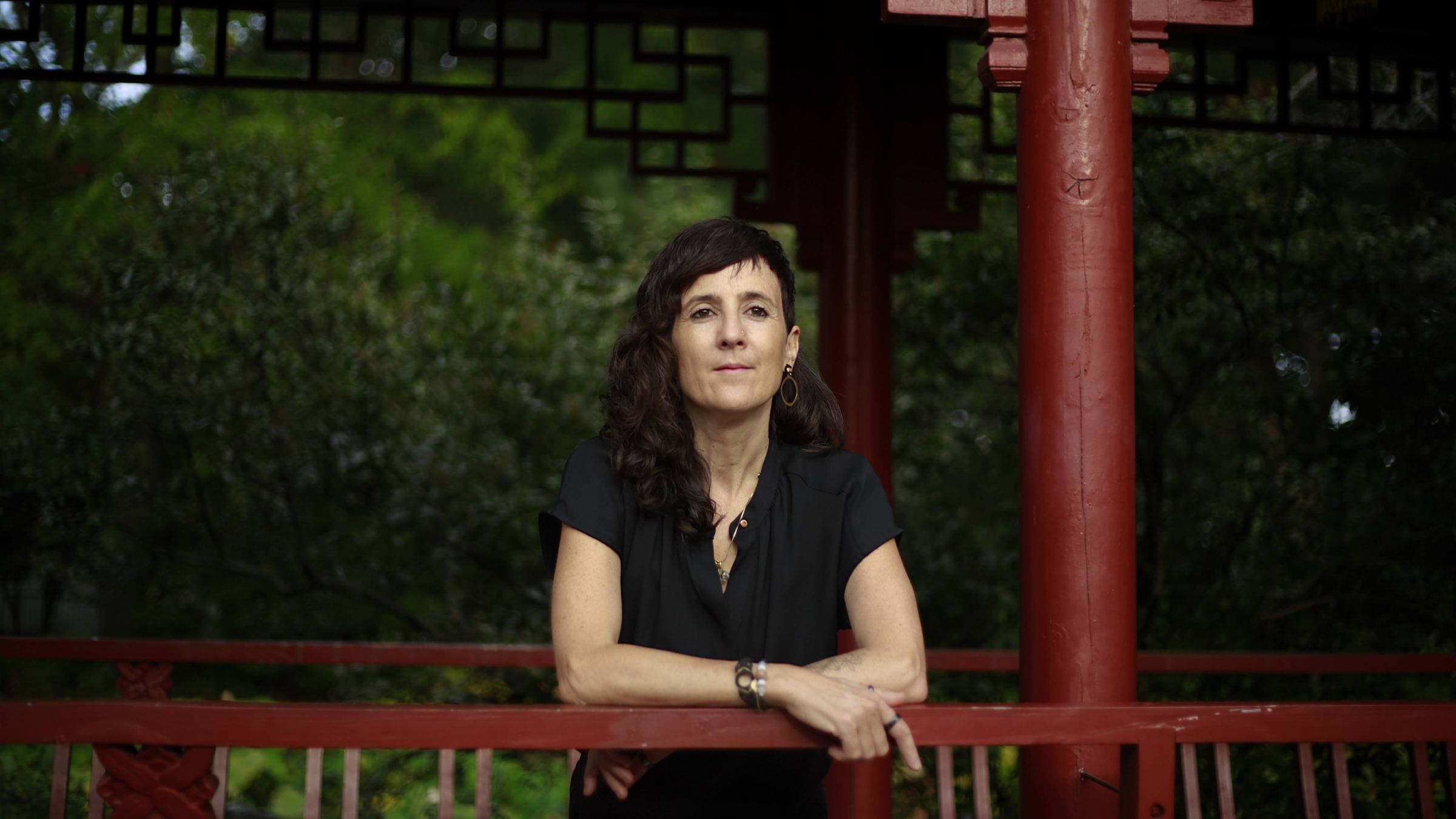 Julie Gazard, leaning on a red railing at the Chinese Garden.